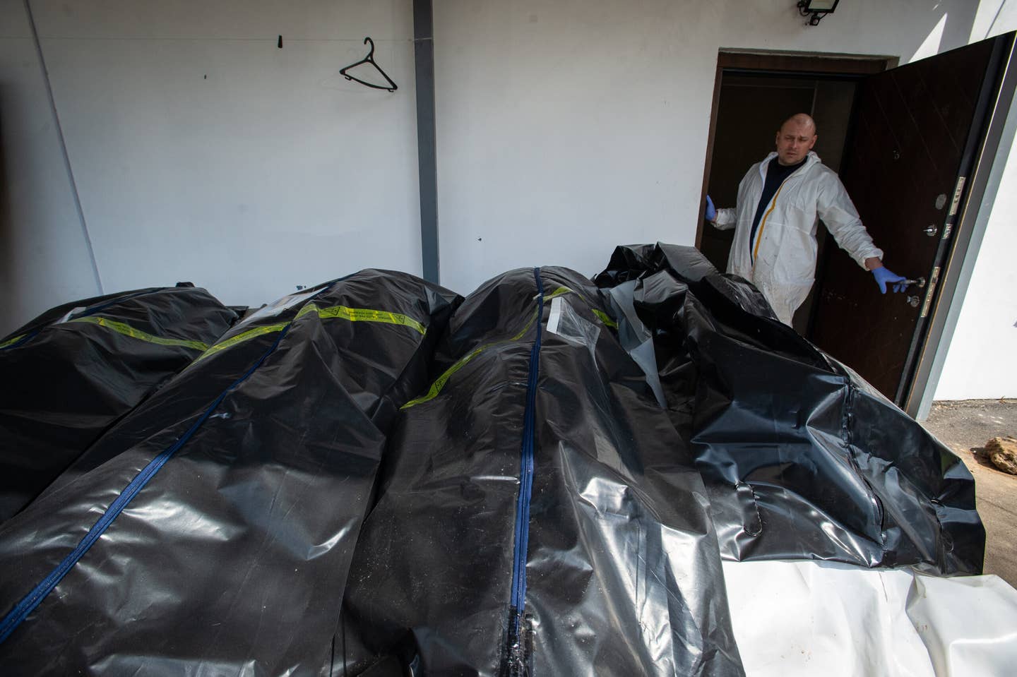 Ukrainian morticians look at body bags full of corpses, as a morgue overflows with victims who died during the Russian military presence in the Kyiv suburb of Bucha, Ukraine, on April 23, 2022. <em>Photo by Scott Peterson/Getty Images</em>