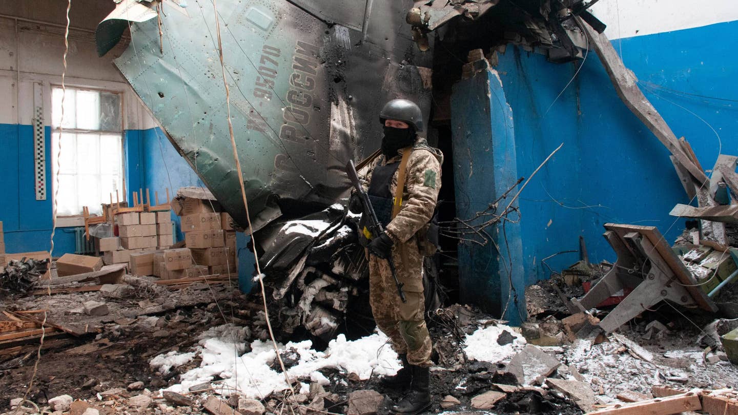 A Ukrainian serviceman stands next to a vertical tail fin from a Russian Su-34 Fullback strike fighter lying in a damaged building in Kharkiv, Ukraine, March 8, 2022. The kind of protracted air war being fought in Ukraine demands a big air force, but that’s not the kind of battle Kendall wants to fight.&nbsp;<em>AP Photo/Andrew Marienko</em>