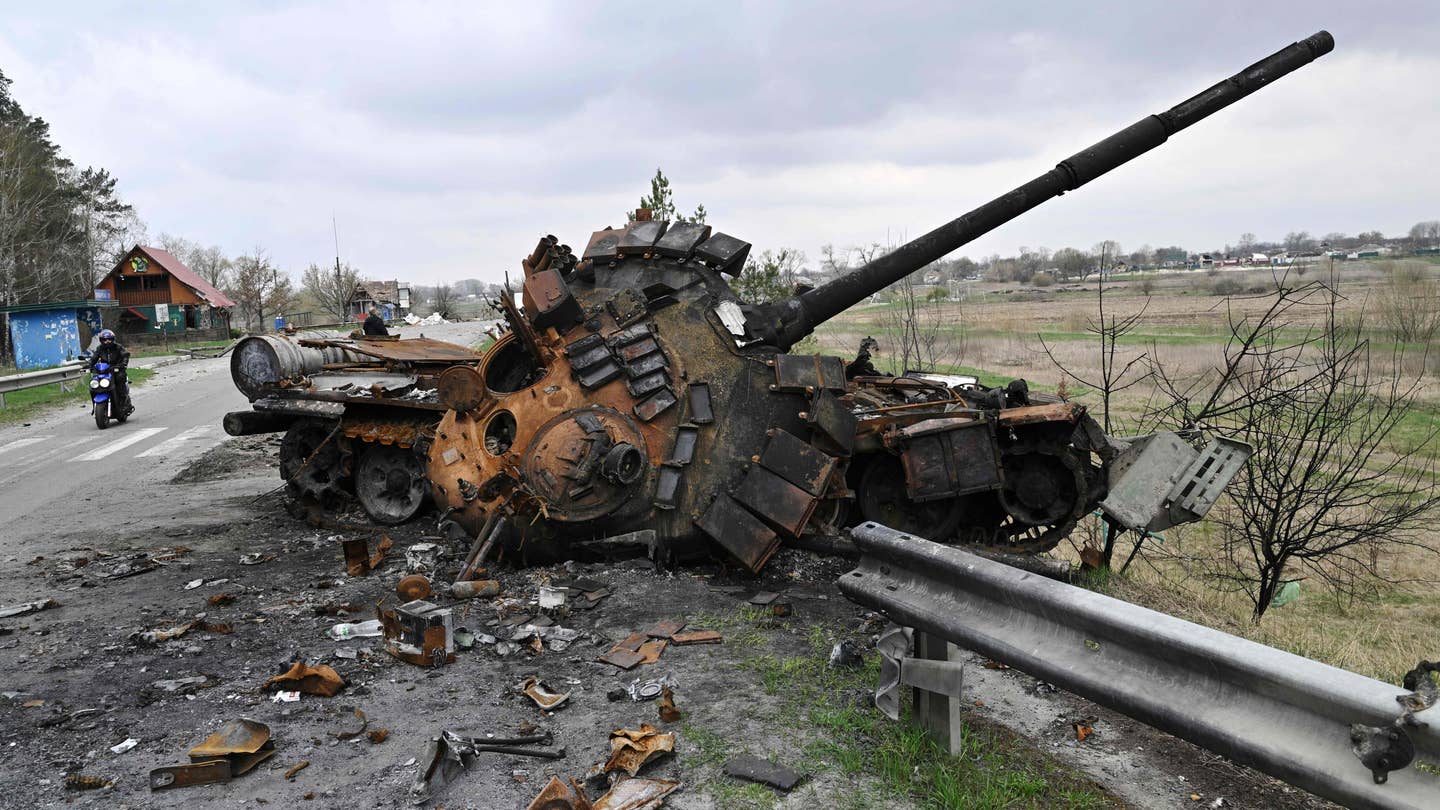 A man ride a motorbike past a destroyed Russian tank on a road in the village of Rusaniv, in the Kyiv region on April 16, 2022. - Many of the nearly five million people who have fled Ukraine will not have homes to return to, the United Nations said on April 16, 2022, as another 40,000 fled the country in 24 hours. (Photo by Genya SAVILOV / AFP) (Photo by GENYA SAVILOV/AFP via Getty Images)
