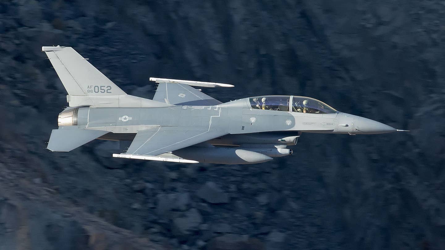 A rare picture of an F-16D Viper that is very likely among those that operate from Area 51. Its crew members are wearing Red Hats and Red Eagles patches. <em>David Atkinson</em>