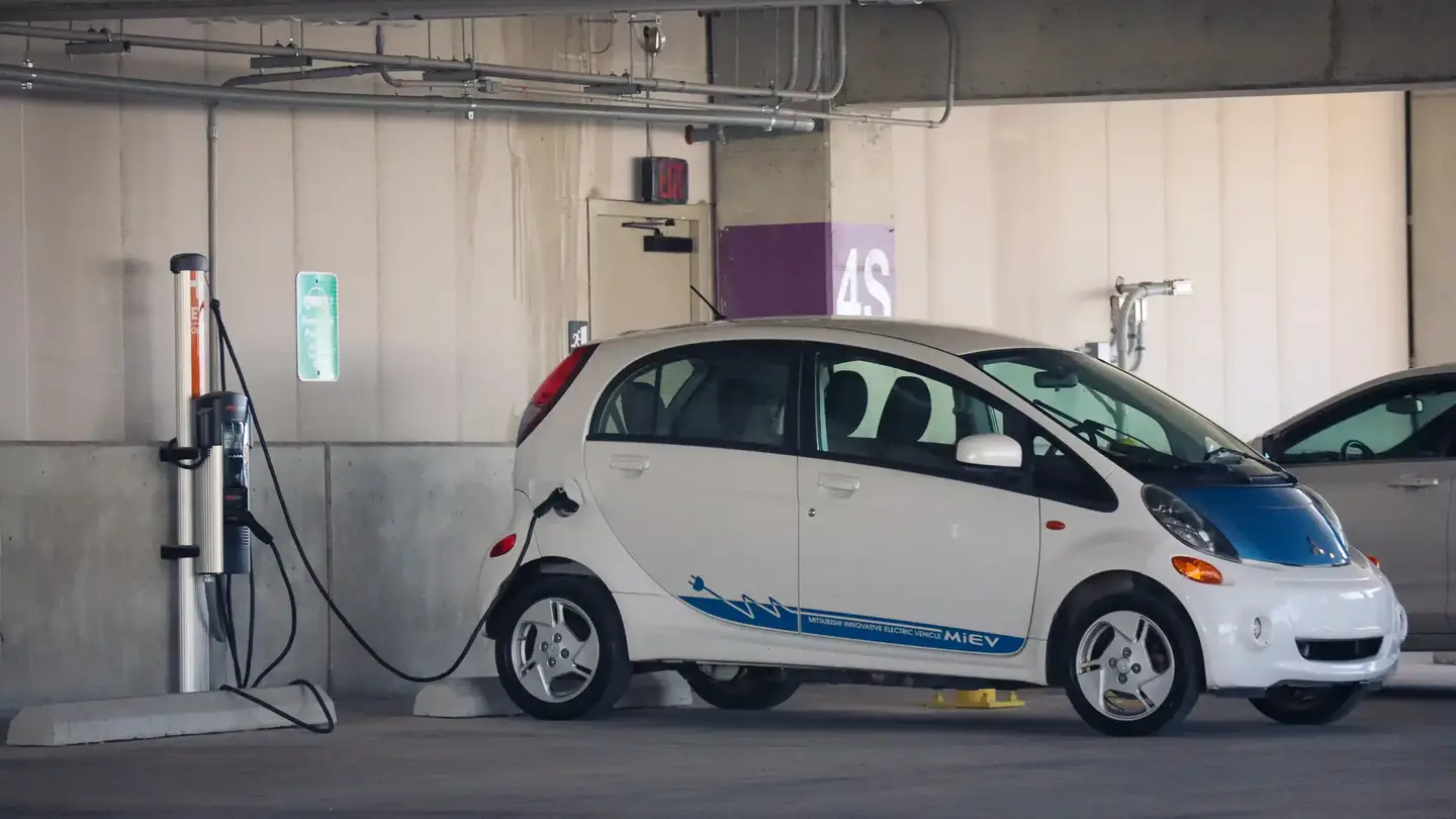 An electric Mitsubishi i-MiEV plugged into a charger.