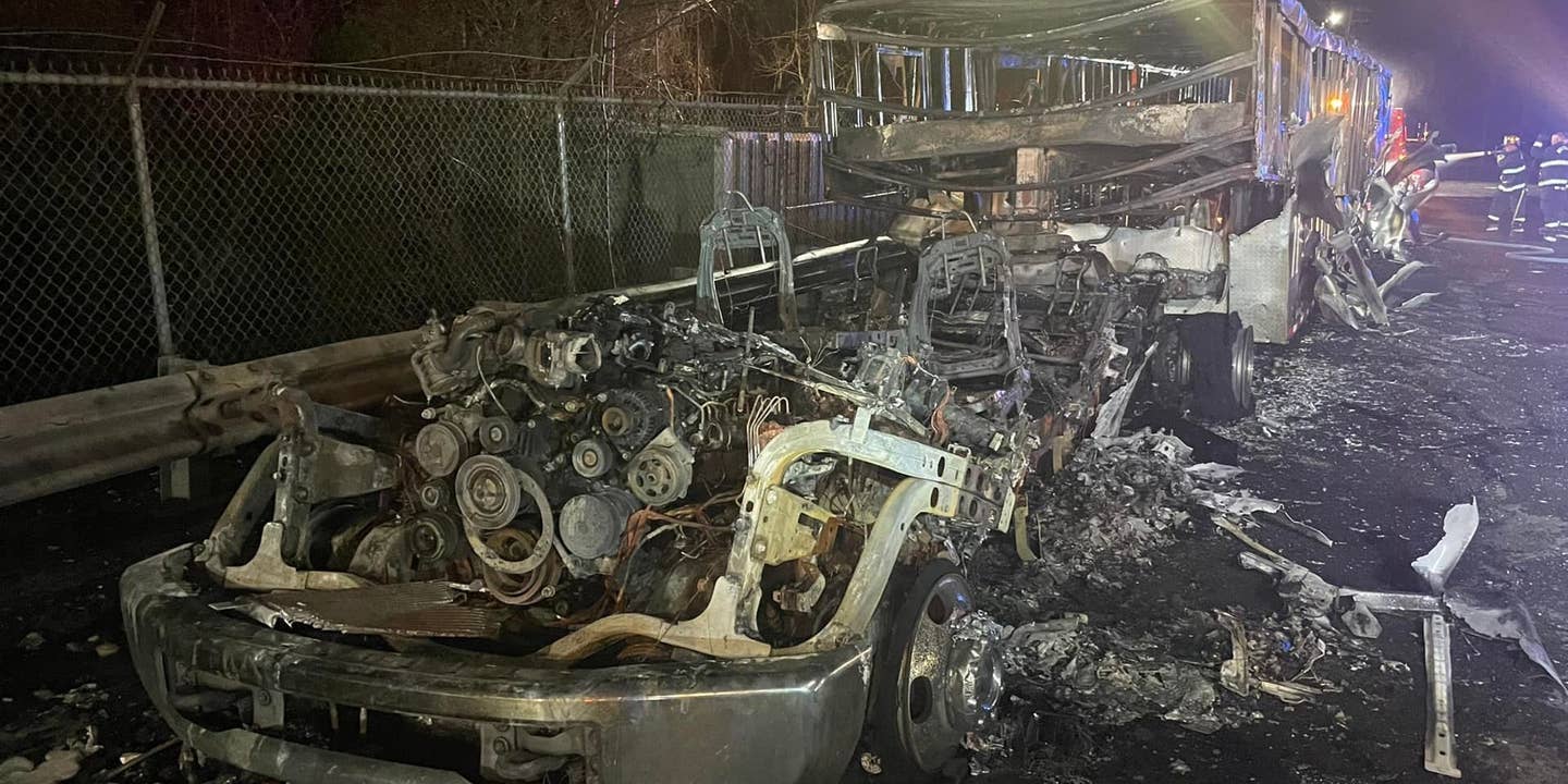 A semi truck and its car carrier trailer burned to a husk. Only the remains of the engine and frame of the truck and trailer remain.