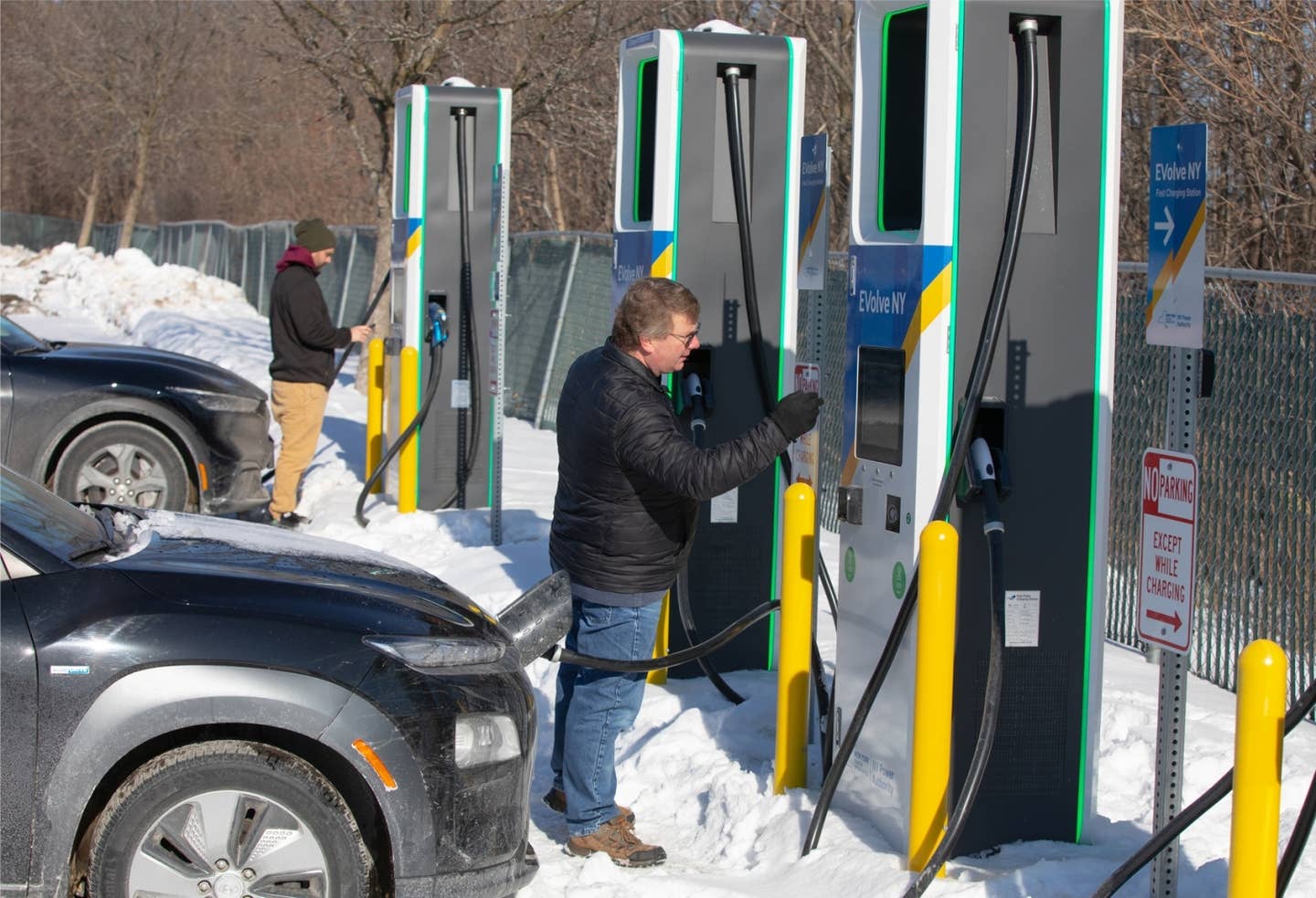 A driver plugging into an Electrify America public charger.