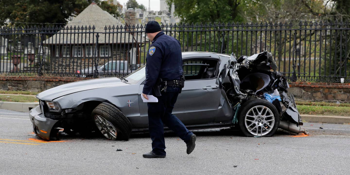 An officer walks past a car involved in a fatal crash