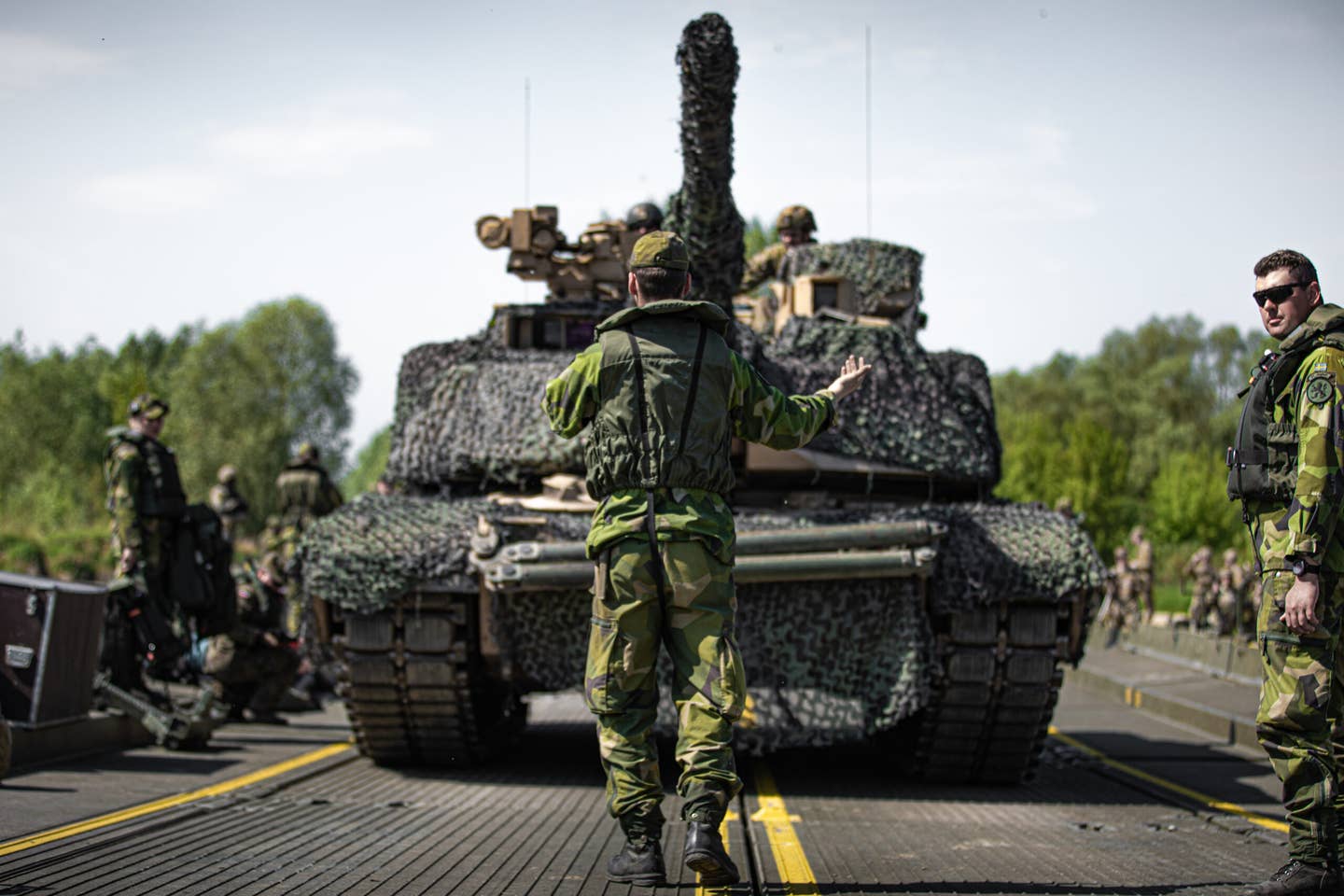 A Swedish soldier guides a U.S. Army M1A2 Abrams tank during a wet-gap crossing at Dęblin, Poland, in May 2022. U.S. Army National Guard photo by Sgt. Agustín Montañez