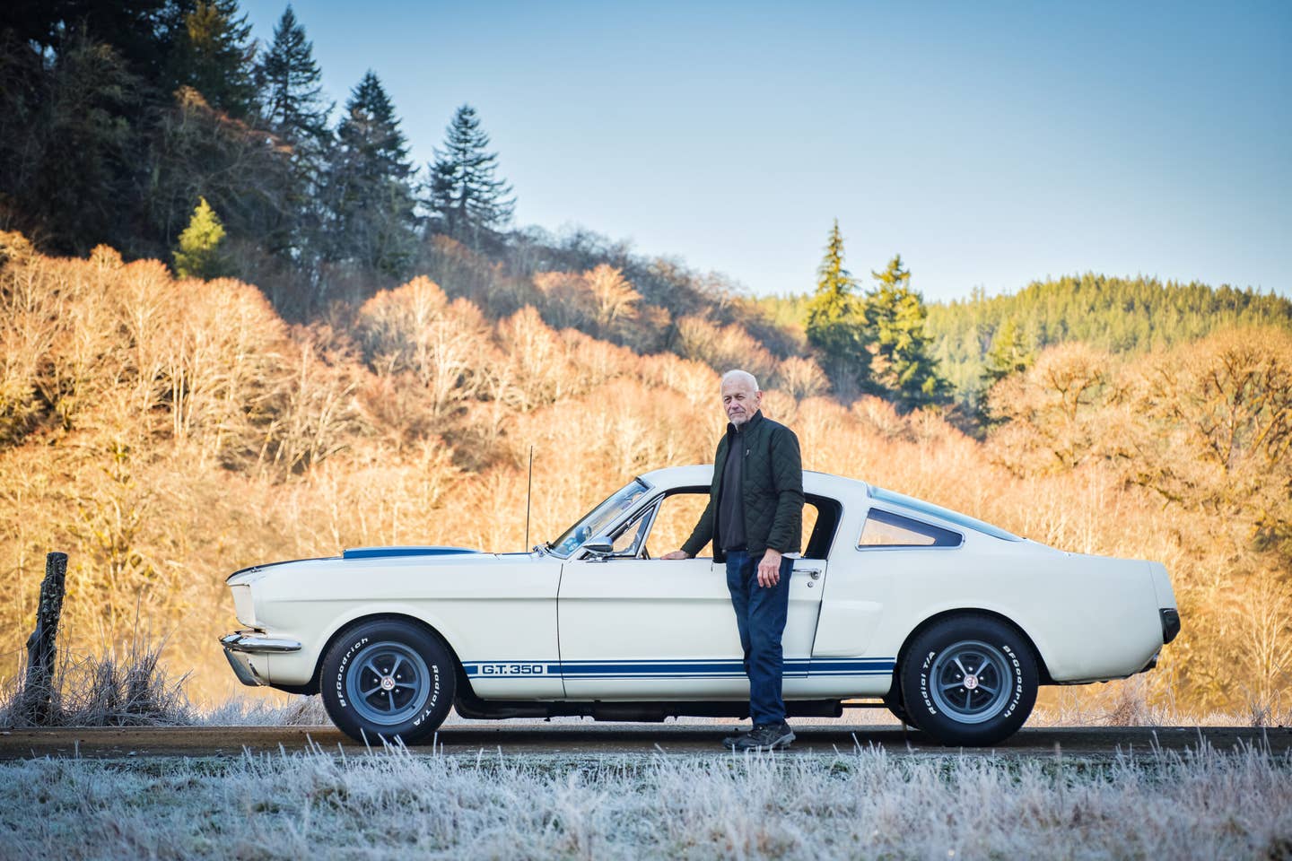 Man standing in front of white Shelby car with blue sky behind him