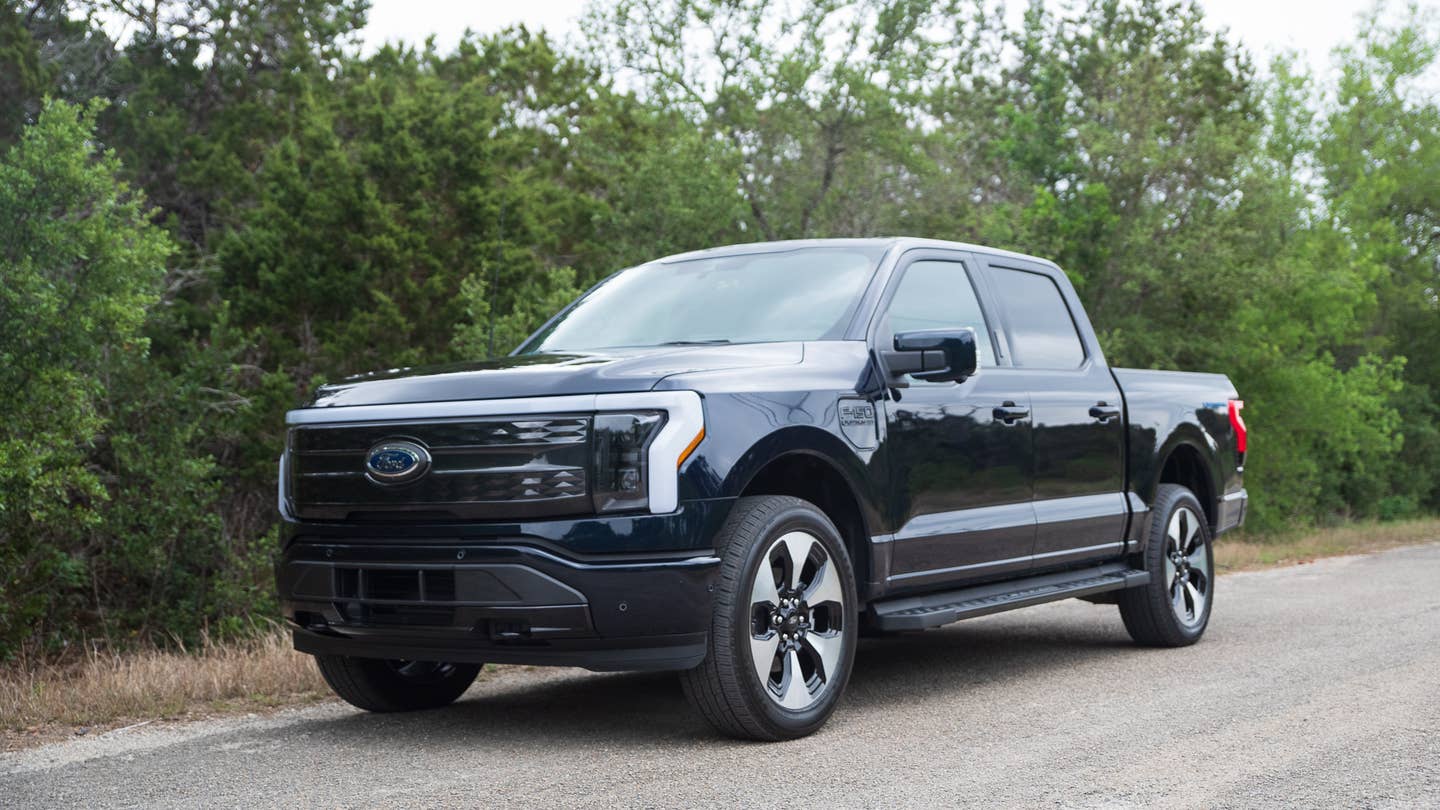2022 Ford F-150 Lightning facing the camera, with shrubbery in the background