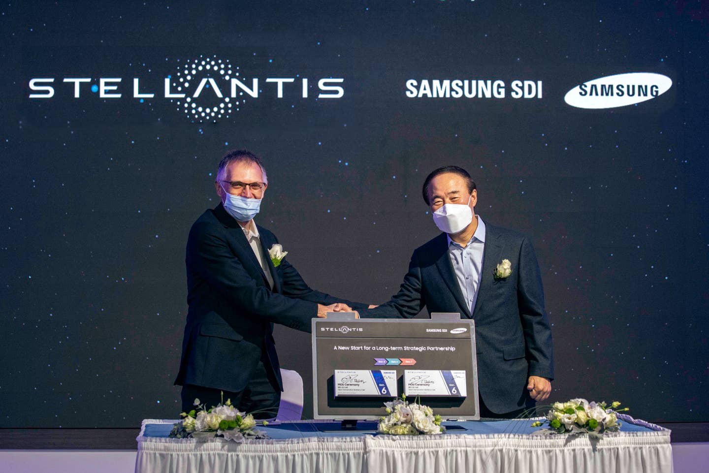 The CEOs of Stellantis and Samsung SDI shake hands to commemorate the new deal.