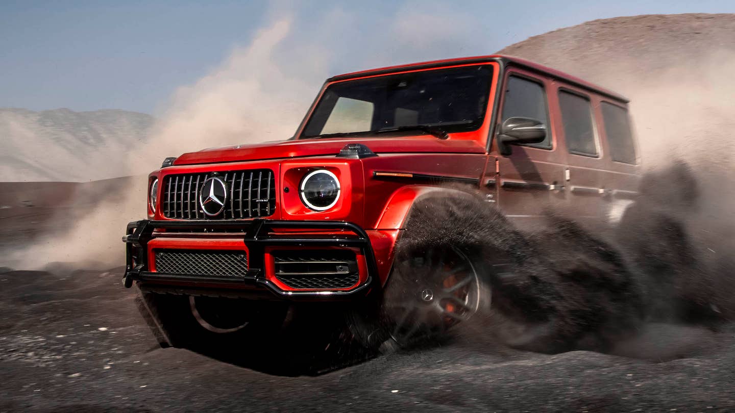 A red Mercedes-AMG G63 throws up clouds of dirt