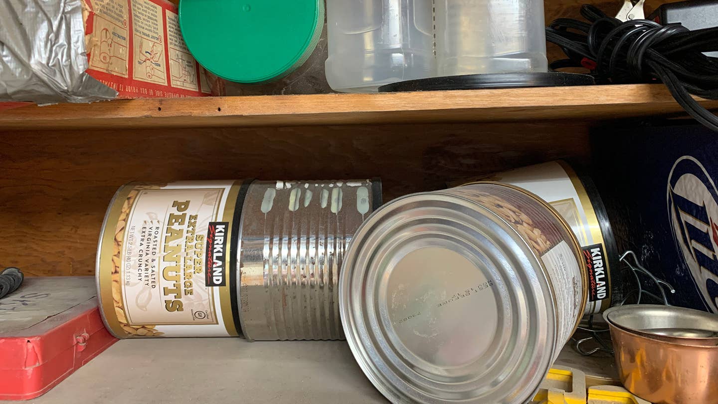 Old peanut tins and coffee cans on a garagee shelf.