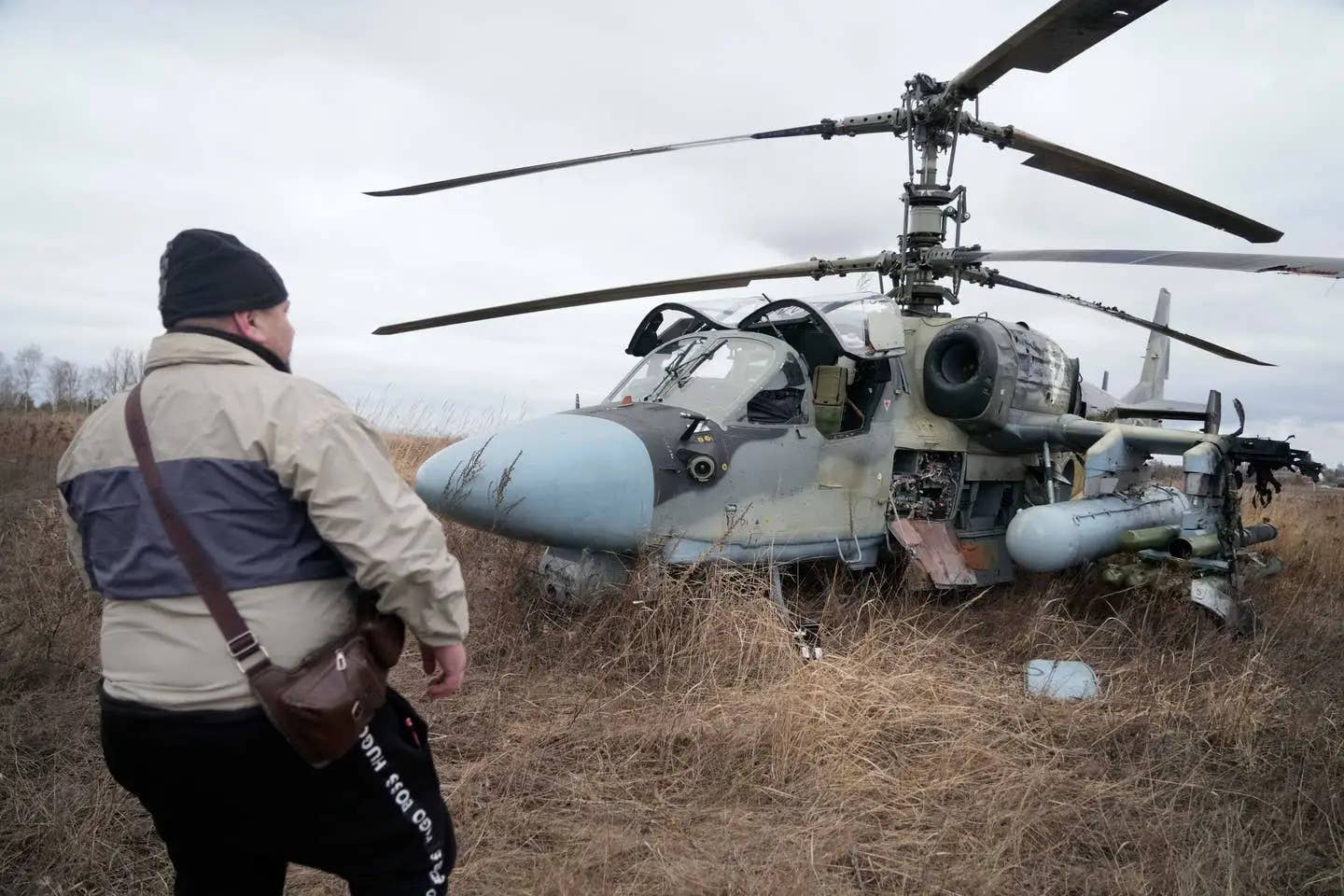 A man stands in front of a Ka-52 attack helicopter forced to land in a field outside Kyiv, Ukraine, on February 24, 2022. AP Photo/Efrem Lukatsky