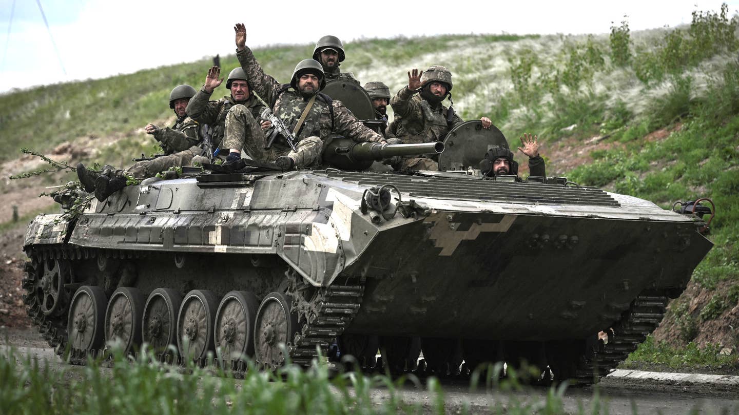 Ukrainian servicemen wave as they move with an armored vehicle toward the frontline at a checkpoint near the city of Lysychansk in the eastern Ukranian region of Donbas, on May 23, 2022, amid Russian invasion of Ukraine.