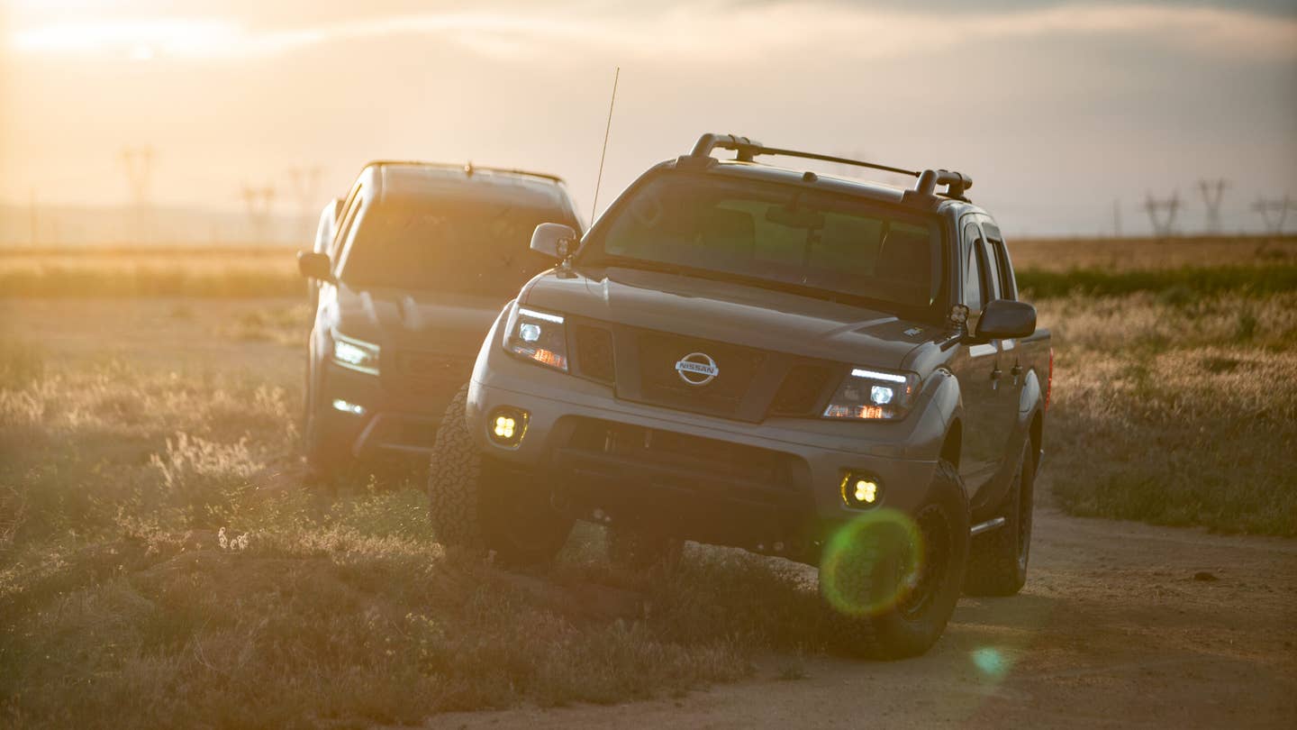 Two Nissan Frontiers posing for a sunset. A desert landscape provides a sweeping backdrop.