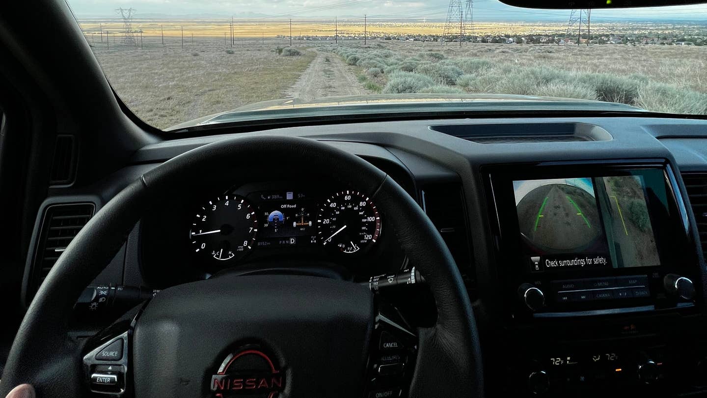 Image of the 2022 Nissan Frontier interior. A desert landscape at sunset sweeps out from the windshield.