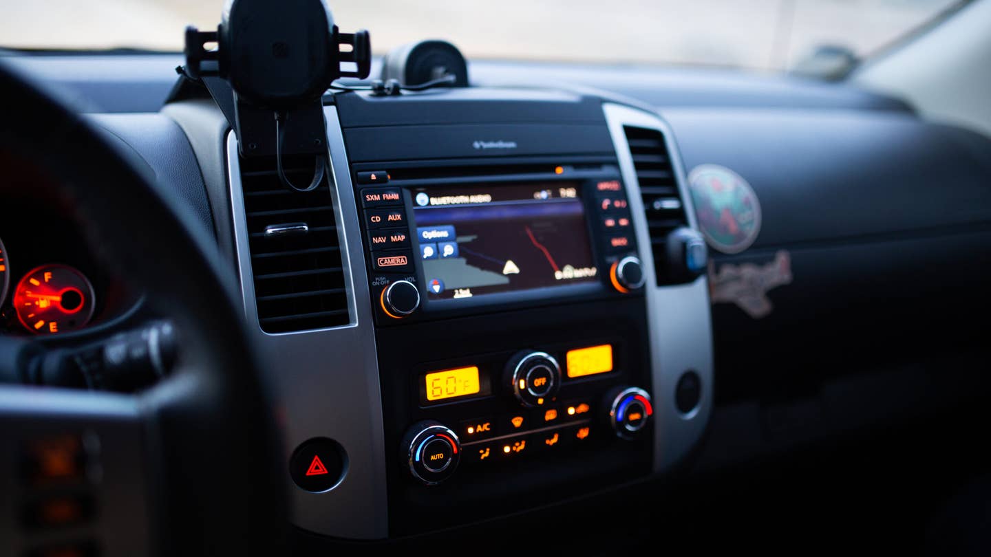 The radio and HVAC controls of a 2020 Nissan Frontier. The buttons are backlit in amber.