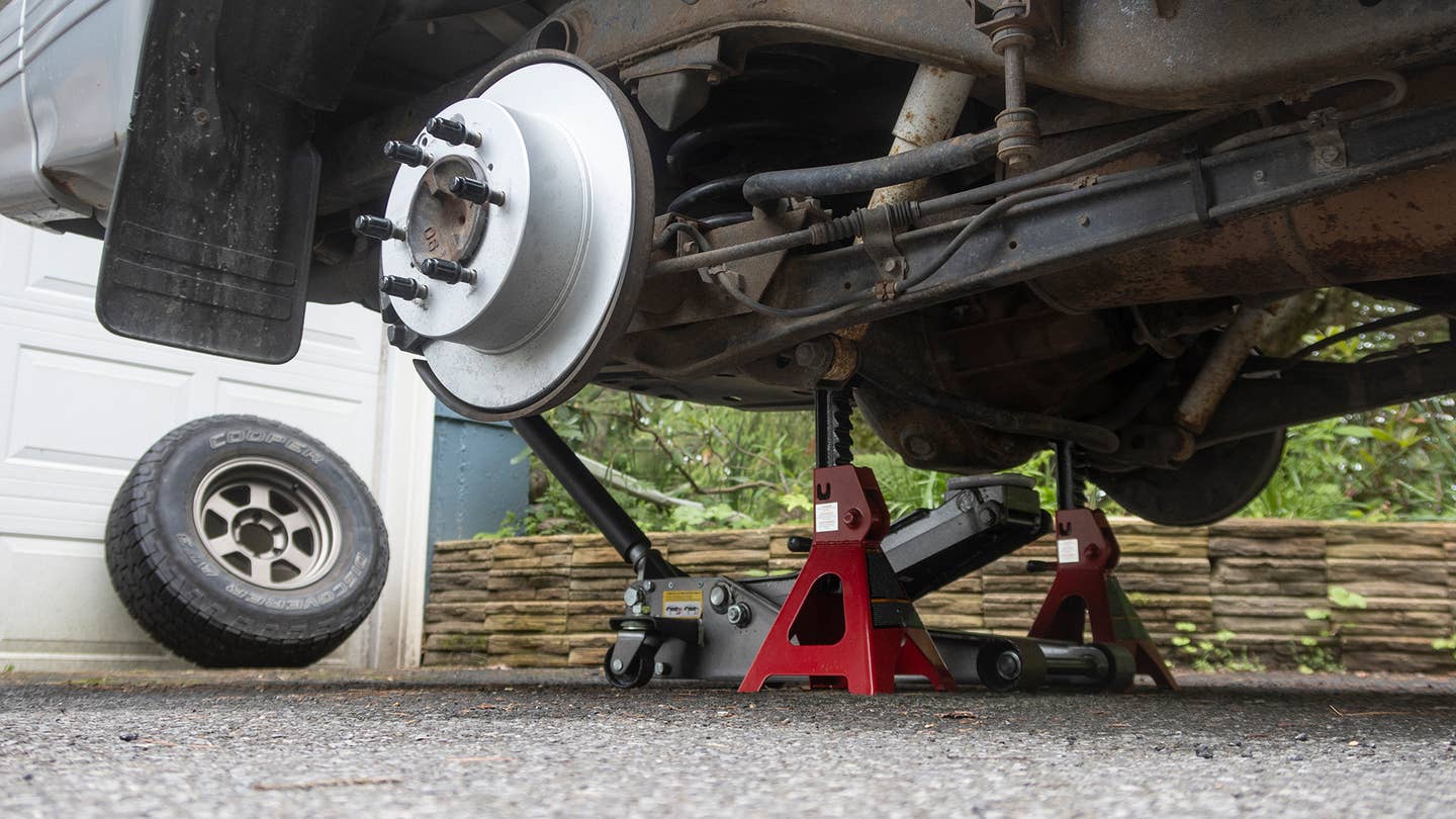 An SUV being supported by jack stands under the rear axle.