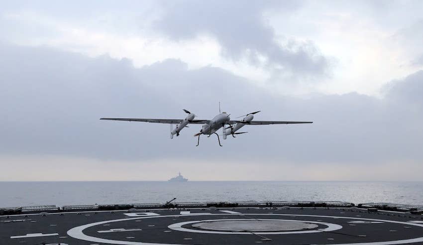 A picture showing a Sea Cavalry SD-40 drone flying above the deck of a PLAN Type 052C destroyer during a test in 2019. <em>China Military Online</em>