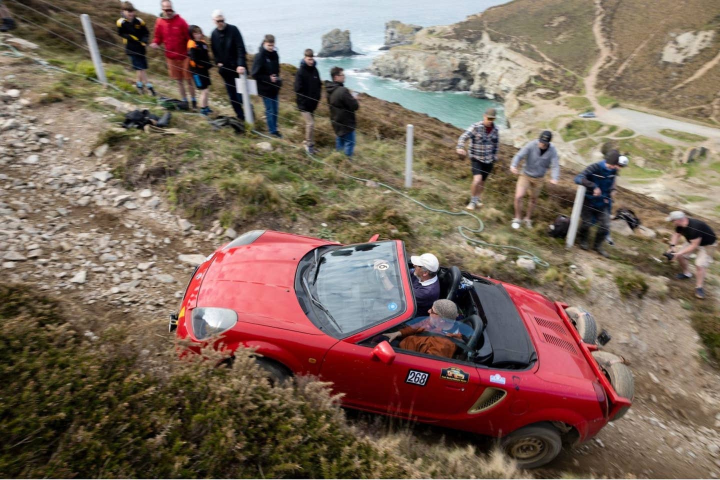 Red car climbing rocky hill