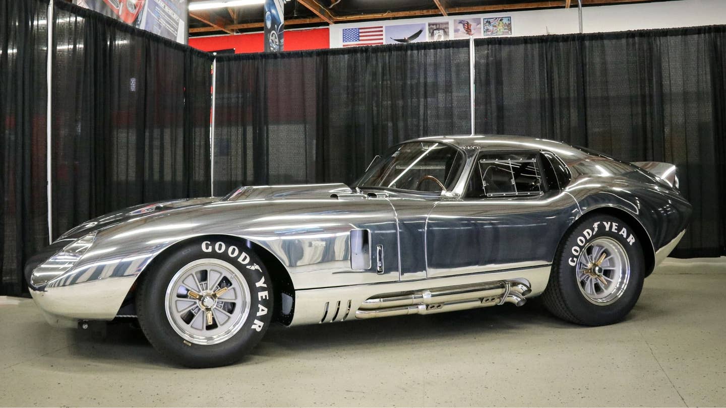 Silver Shelby in front of black curtains