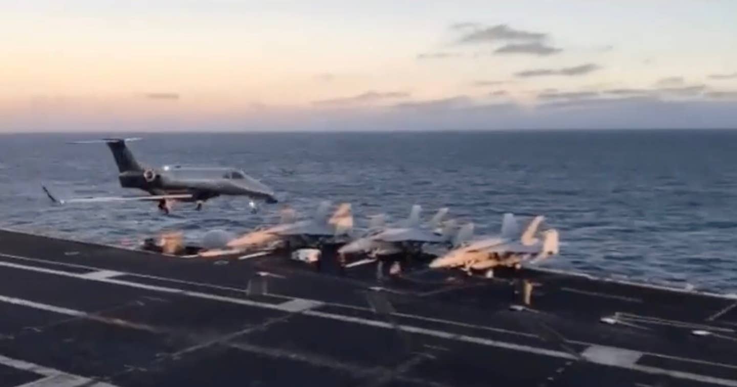 A still from the footage posted by LaRosa depicting the Embraer Phenom jet flying above the landing area of the supercarrier. What a bizarre moment, definitely a first. <em>@k2_larosa/Kevin LaRosa.  </em>