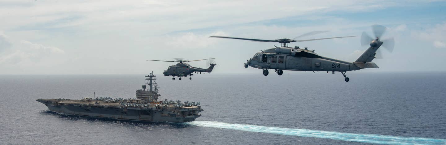 A Republic of Korea Navy Lynx helicopter and a U.S. Navy MH-60S Seahawk in formation near the USS <em>Ronald Reagan</em> (CVN-76) during the Carrier Strike Group Exercise 2022. <em>U.S. Navy photo by Mass Communication Specialist 2nd Class Michael B. Jarmiolowski</em>