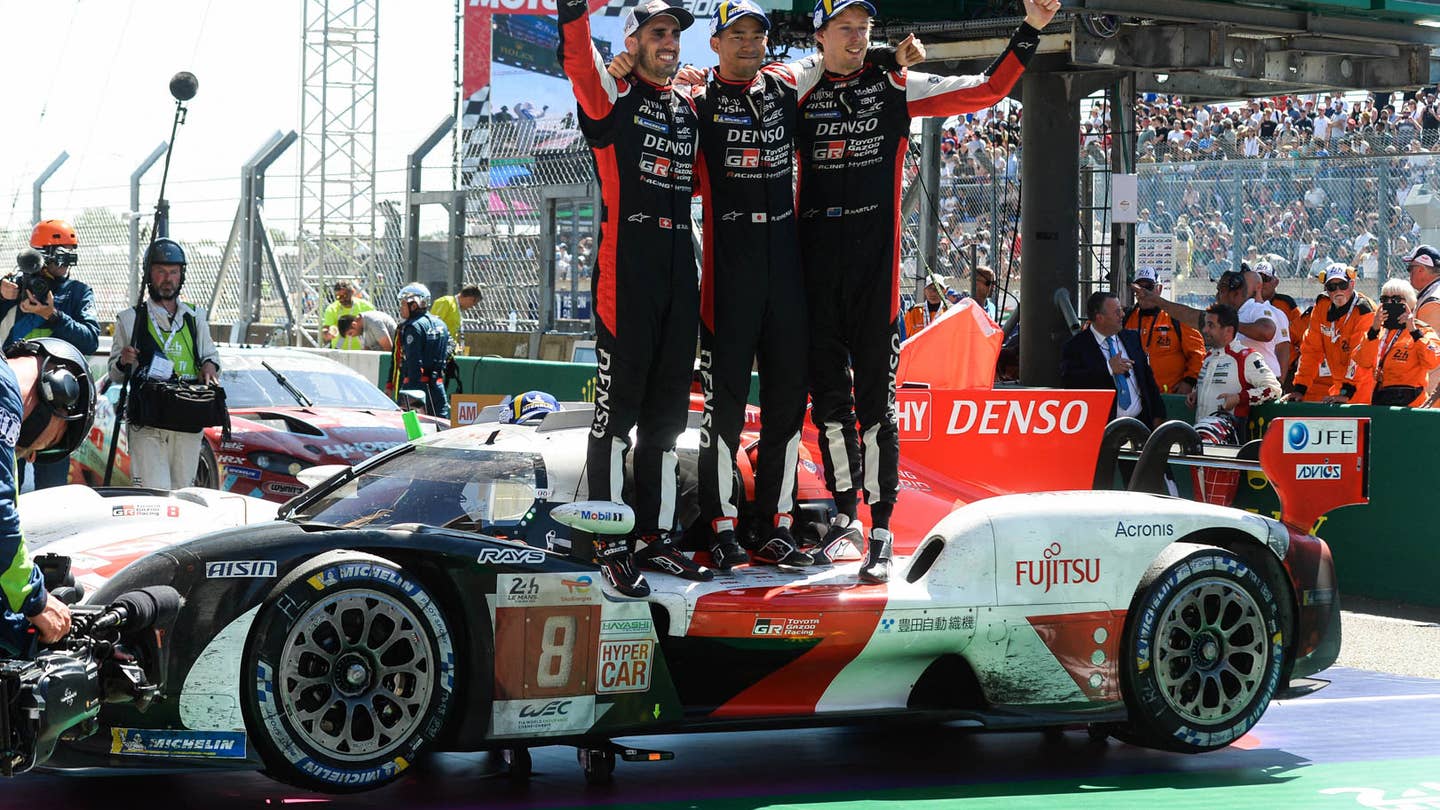 (From L) Drivers of the Toyota number 8 GR010 Hybrid Hypercar Swiss Sebastien Buemi, Japanese Ryo Hirakawa and New Zealand Brendon Hartley celebrate after winning at the end of the 90th edition of the Le Mans 24 Hours endurance race, in Le Mans, north-western France, on June 12, 2022. (Photo by JEAN-FRANCOIS MONIER / AFP) (Photo by JEAN-FRANCOIS MONIER/AFP via Getty Images)