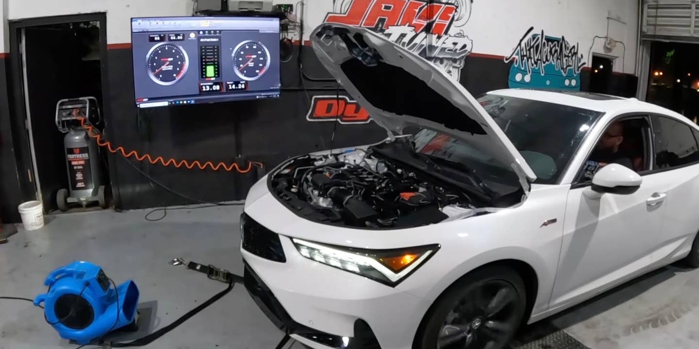 A white 2023 Acura Integra is strapped to a dyno with its hood open.