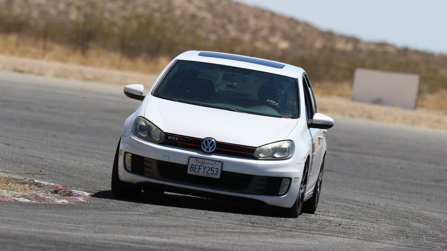A white 2010 Volkswagen GTI entering the final turn at Streets of Willow handling course. It is mobbing.