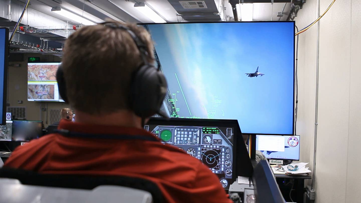 Donald Simones, a subject matter expert in the Air Force Research Laboratory’s 711th Human Performance Wing, flies a virtual F-16 in a Deployable Tactical Trainer during the SLATE Phase III capstone demonstration at Nellis Air Force Base, Nevada in September 2018. The live aircraft, such as the one shown on the screen, were able to see and interact with the virtual players like Simones during the demonstration. <em>U.S. Air Force photo/William Graver</em>