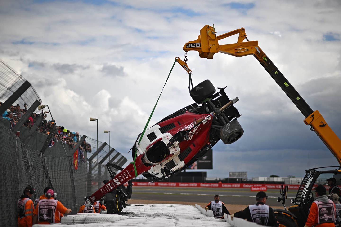 TOPSHOT - Stewards remove the crashed car of Alfa Romeo Chinese driver Zhou Guanyu from the barriers after a crash at the start of the Formula One British Grand Prix at the Silverstone motor racing circuit in Silverstone, central England on July 3, 2022. (Photo by Ben Stansall / AFP) (Photo by BEN STANSALL/AFP via Getty Images)