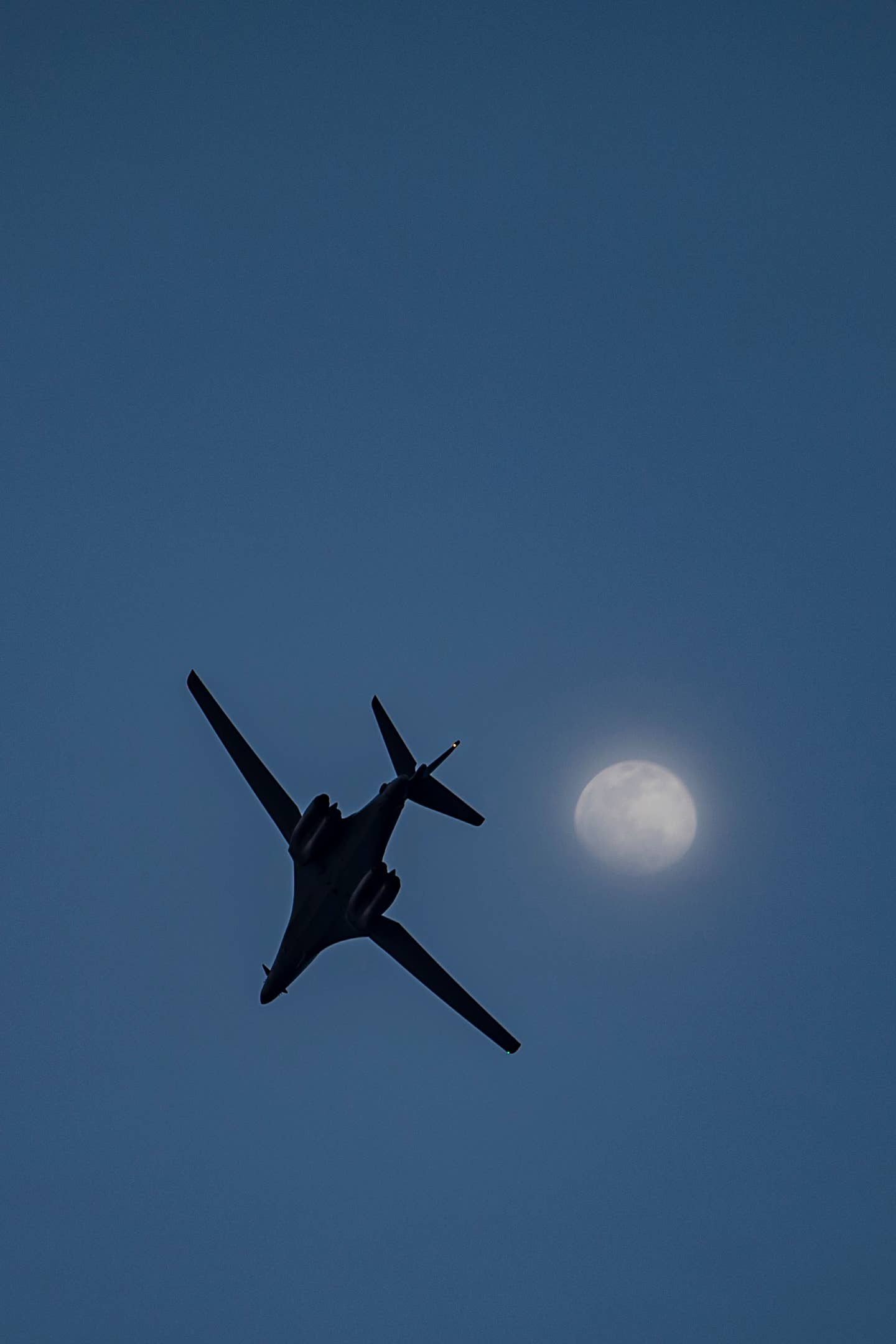 A B-1B flies under the moon at Andersen Air Force Base, Guam, June 12, 2022. <em>U.S. Air Force photo by Tech. Sgt. Chris Hibben</em>