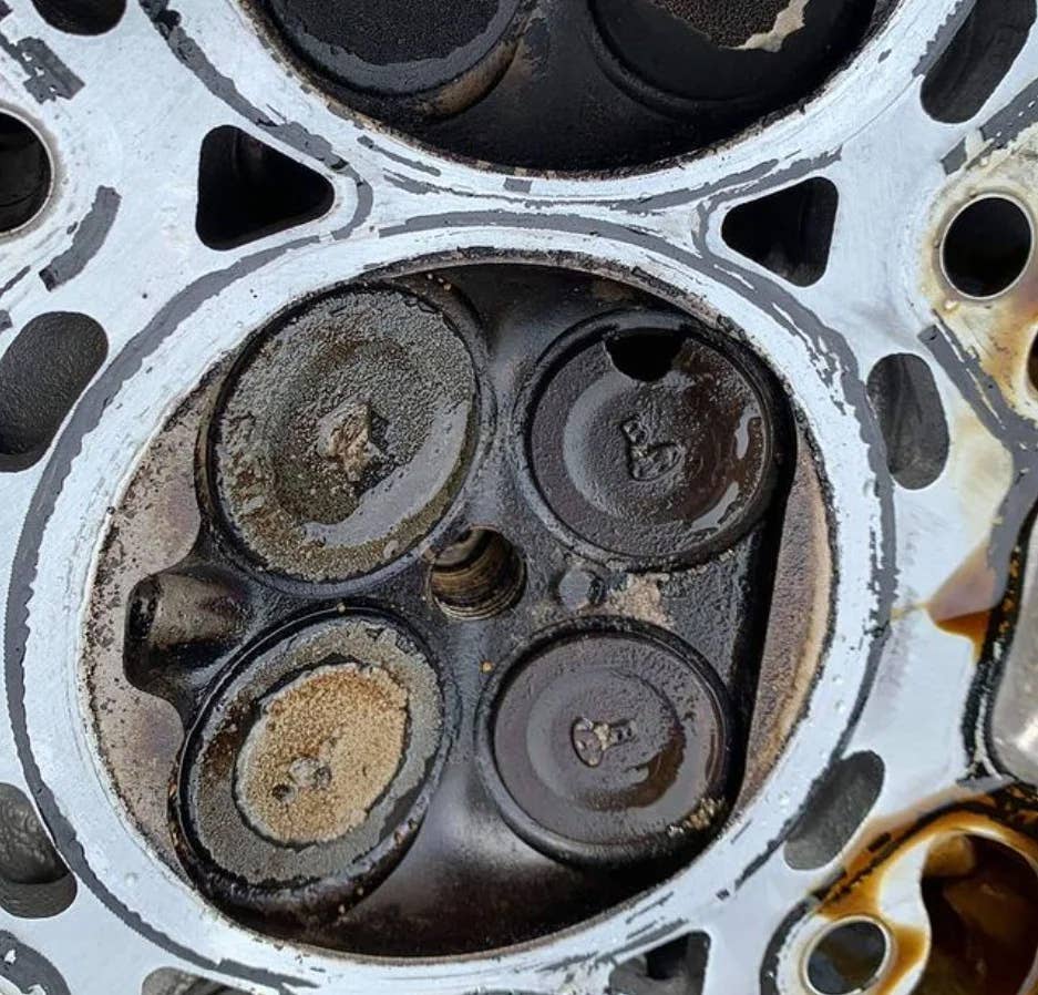 Carbon covered valves, with one chunk missing sitting in cylinder head