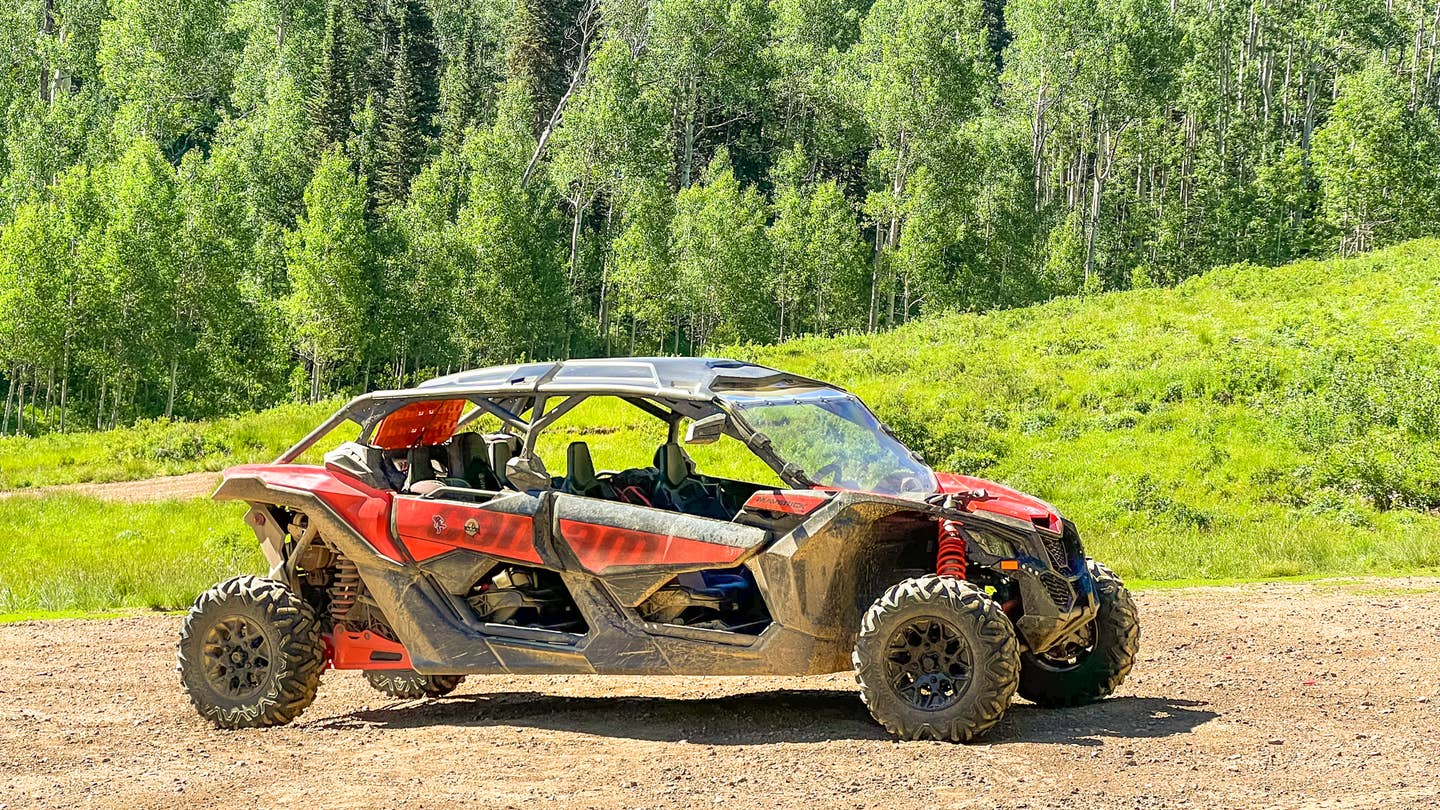 A Can-Am Maverick X3 in a field with trees.