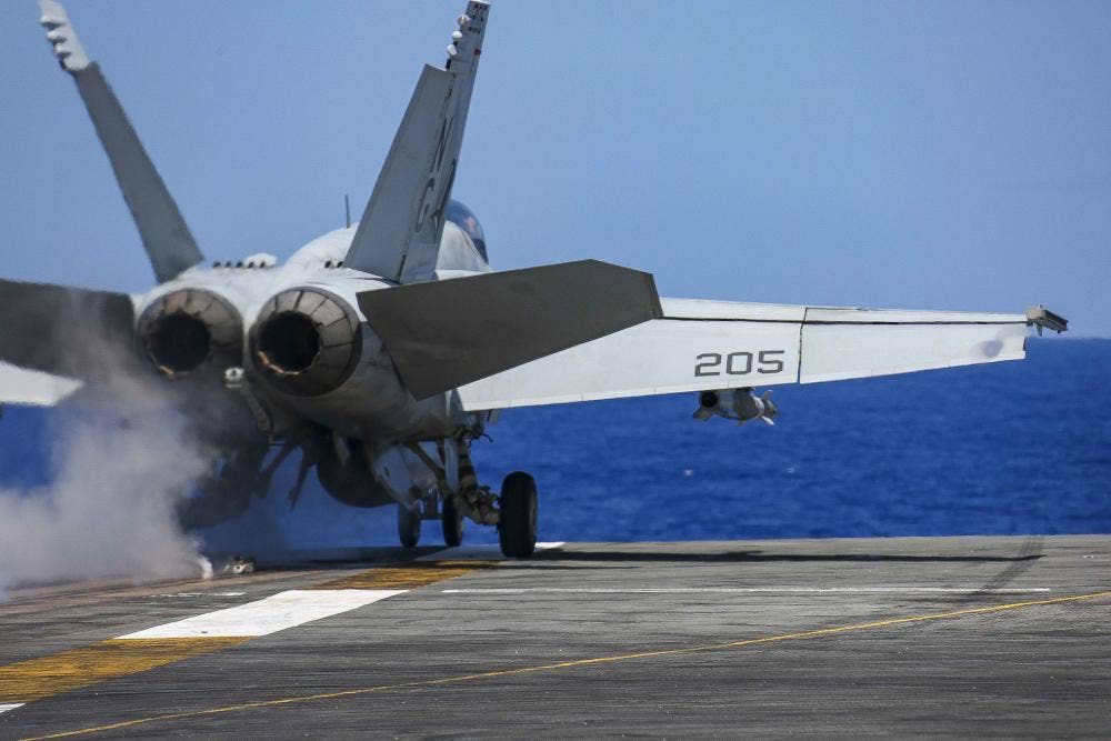An F/A-18E Super Hornet from Strike Fighter Squadron 14 "Tophatters" (VFA-14) loaded with a Paveway laser-guided bomb takes off from the USS <em>Abraham Lincoln</em> during a SINKEX at RIMPAC 2022. (DVIDS/MC3 Javier Reyes).