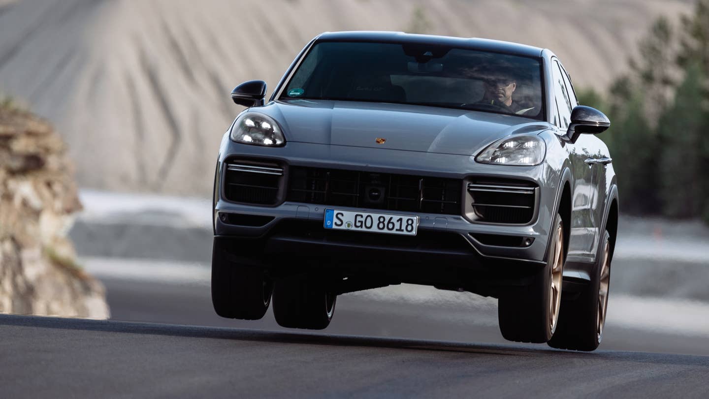 A Porsche Cayenne Turbo GT at full send, catching air on a race track.