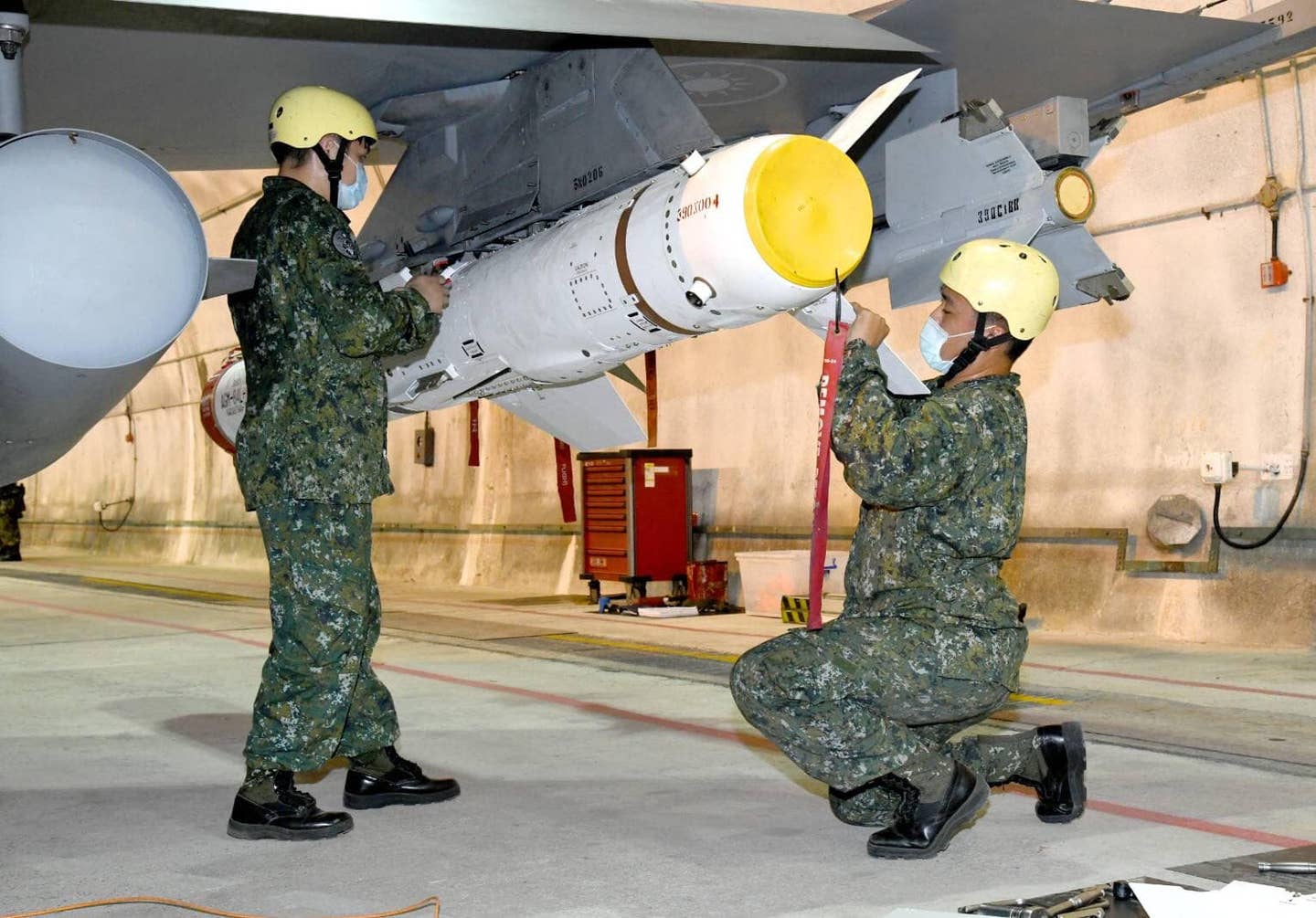 Two ROCAF crewmembers load a Harpoon anti-ship missile onto an F-16 in Chiashan's underground hangar during a weapons loading exercise. <em>Credit: ROCAF</em>