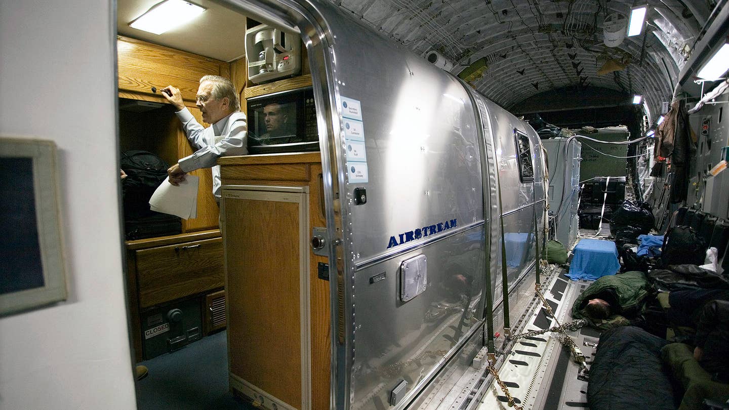 Secretary of Defense Donald Rumsfeld in an Airstream trailer aboard an Air Force C-17 as he heads to Iraq, December 8,  2006. His aide, Colonel Will Grimsley, is reflected in the microwave. The trailer is used for VIPs traveling aboard the cargo plane, and is securely fastened to the floor.  (Photo by David Hume Kennerly/Getty Images)