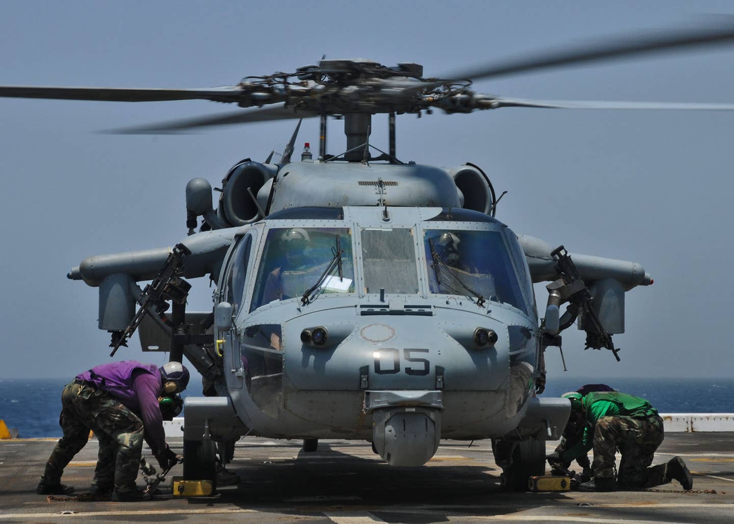 Sailors aboard the amphibious transport dock ship USS <em>New York</em> tie down an MH-60S Sea Hawk helicopter from Helicopter Sea Combat Squadron (HSC) 22 to the ship's flight deck. <em>Credit: Mass Communication Specialist 2nd Class Zane Ecklund/U.S. Navy</em>