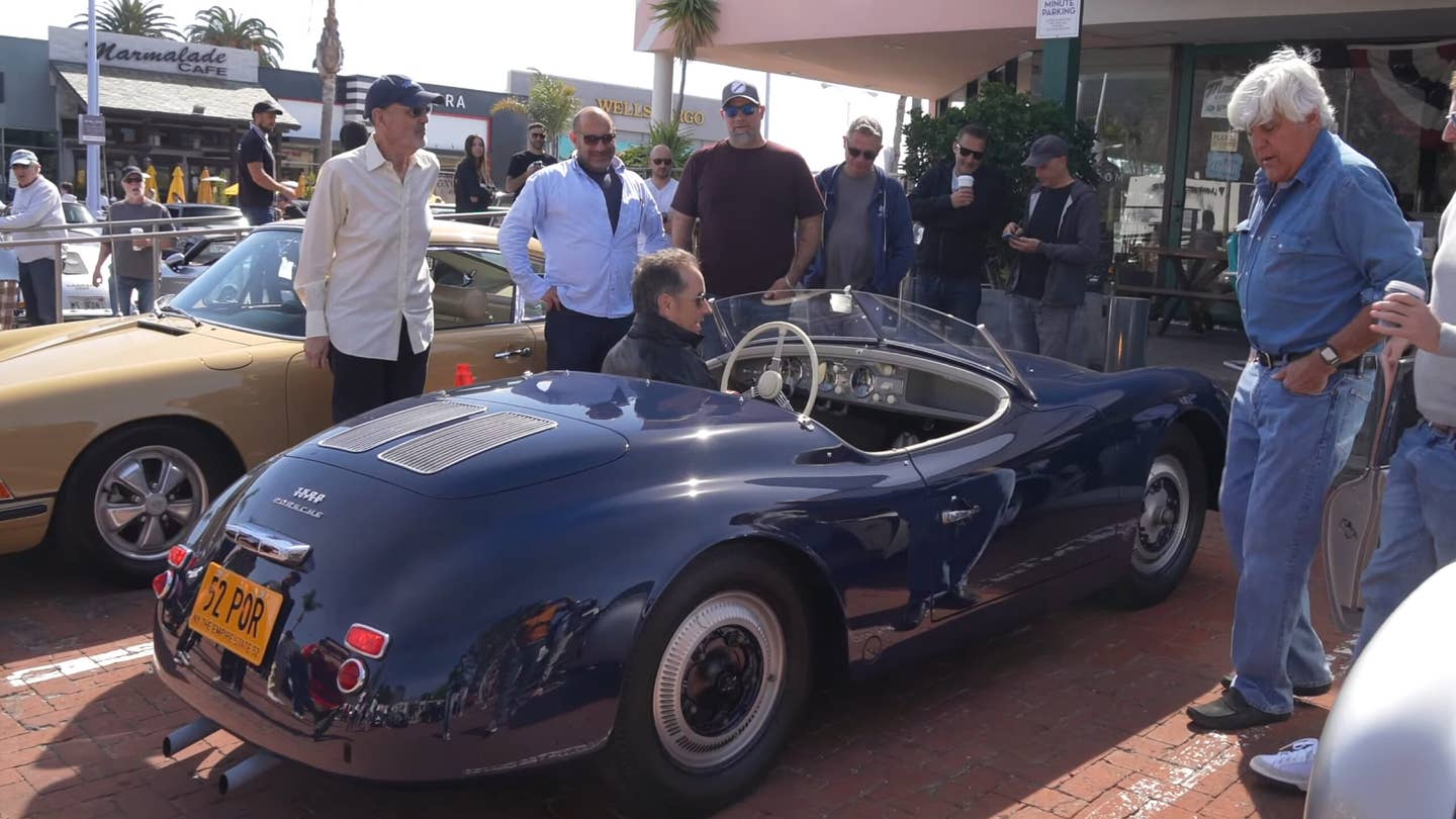 Jerry Seinfeld pulls up in a 356 America Roadster as Jay Leno and others look on.