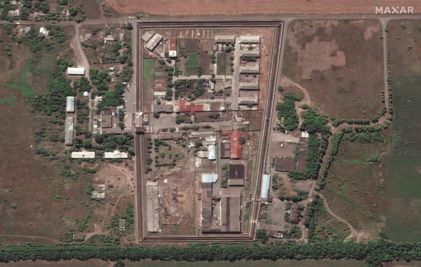 A satellite image of Olenivka prison from July 27 with seven vertical lines of open graves near the south wall at the top of the image. (Maxar Technologies / July 27, 2022).