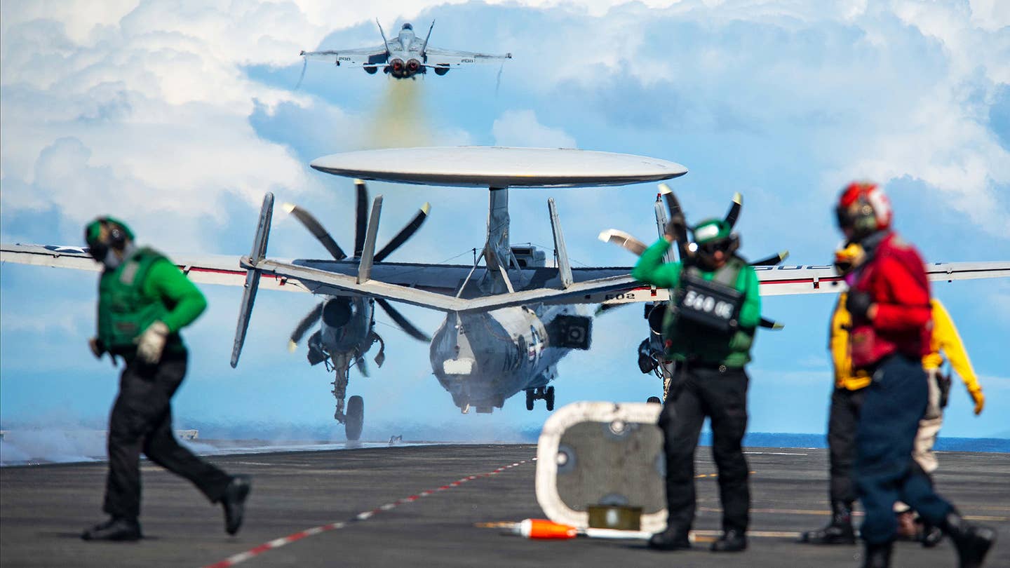 An E-2D follows a Super Hornet off the deck. (<em>USN photo)</em>