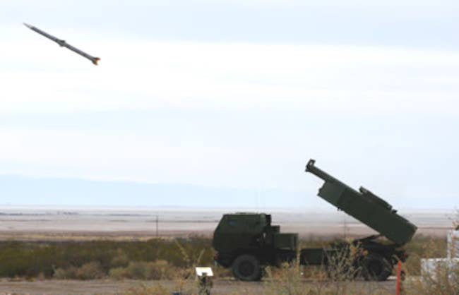 A picture showing an M142 HIMARS launch vehicle firing an AIM-120 AMRAAM missile. <em>Public Domain</em>