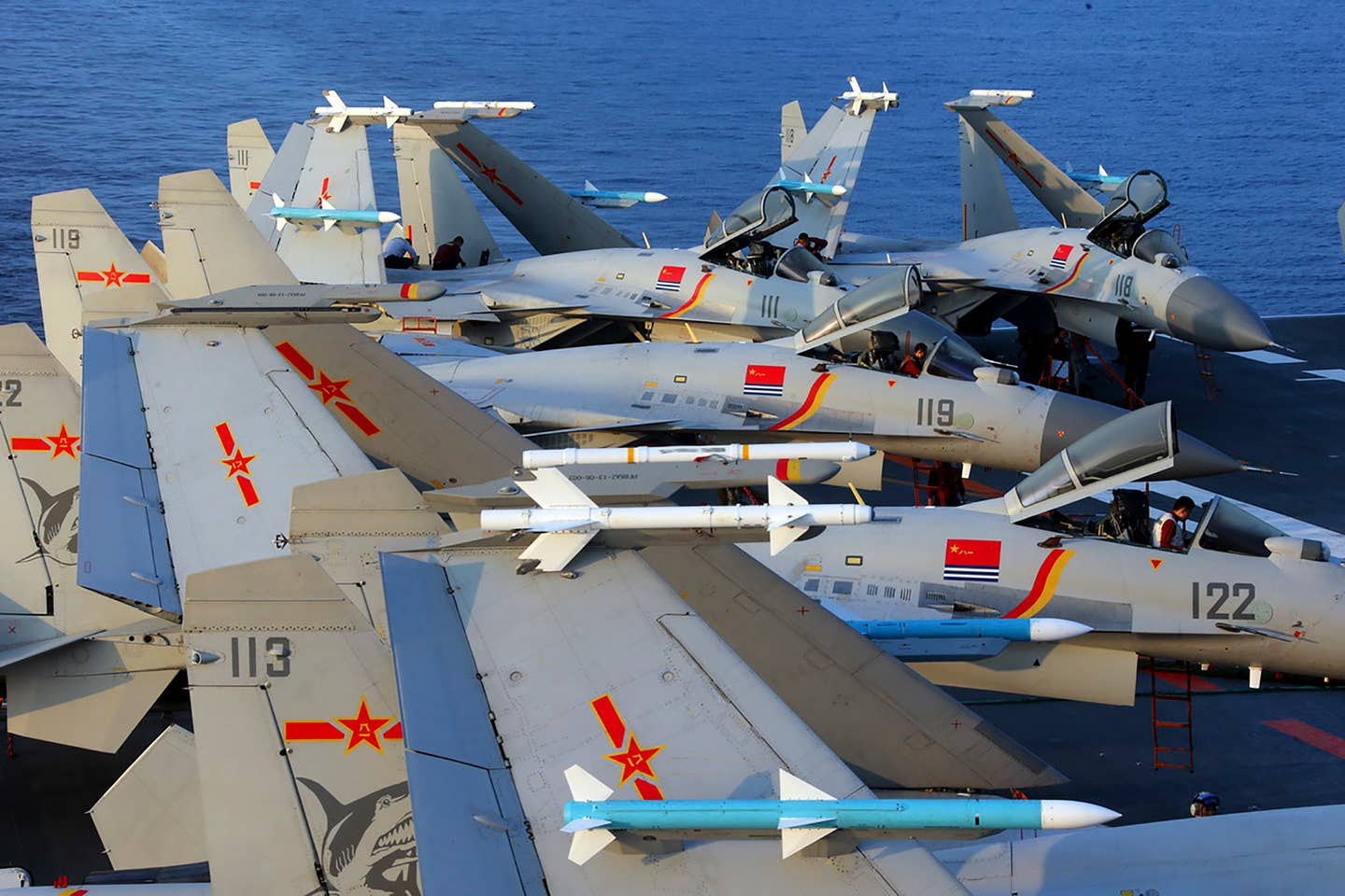 J-15 carrier fighters on the deck of the aircraft carrier <em>Liaoning</em>. The blue-colored missiles are inert PL-12s, with a mixture of PL-8s and air combat maneuvering instrumentation pods on the wingtip stations. <em>AFP via Getty Images</em>