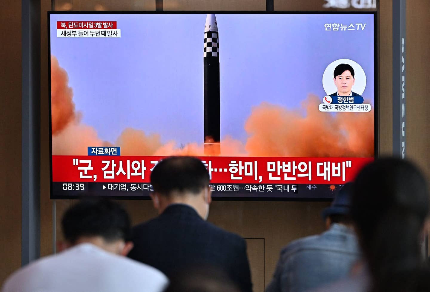 People watch a television screen showing a news broadcast with file footage of a North Korean missile test, at a railway station in Seoul on May 25, 2022, after North Korea fired three ballistic missiles toward the Sea of Japan. <em>Photo by JUNG YEON-JE/AFP via Getty Images</em>