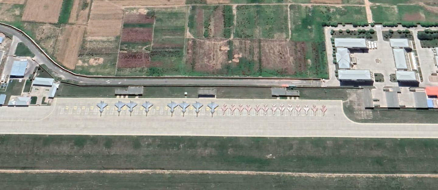Eight J-20-style ‘shapes’ and 13 J-7 fighter jets lined up on the north apron at Lintao Air Base in July. <em>Google Earth</em>