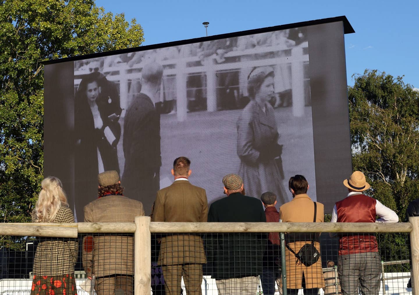 People watch a video in tribute to Queen Elizabeth II before observing a minute's silence during the Goodwood Revival 2022 at Goodwood Motor Circuit in West Sussex. <em>Matt Alexander/PA Wire</em>