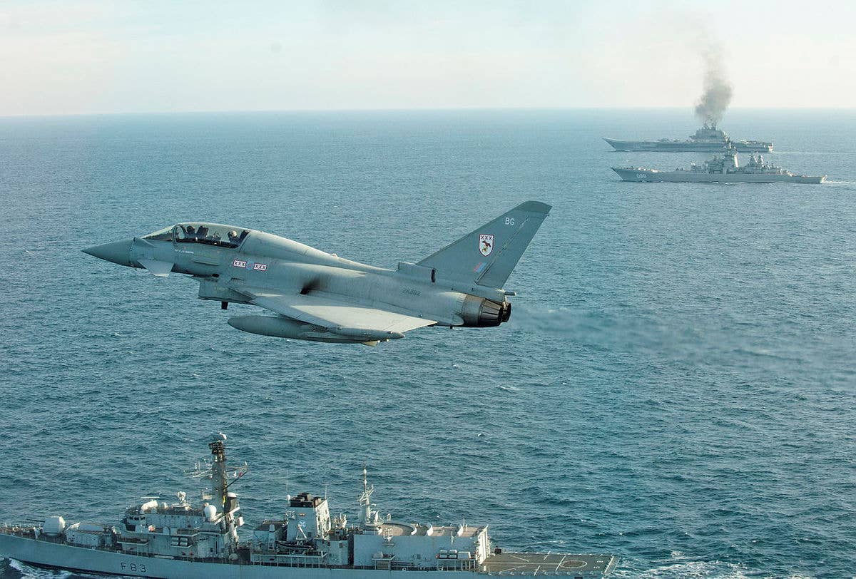 An RAF Typhoon, together with the frigate HMS <em>St Albans</em> seen here in the foreground, shadow the Russian Navy <em>Kirov</em> class battlecruiser <em>Petr Velikiy</em> (center) and the aircraft carrier <em>Admiral</em> <em>Kuznetsov</em> (background) as they transit the English Channel in 2017. <em>Crown Copyright</em>