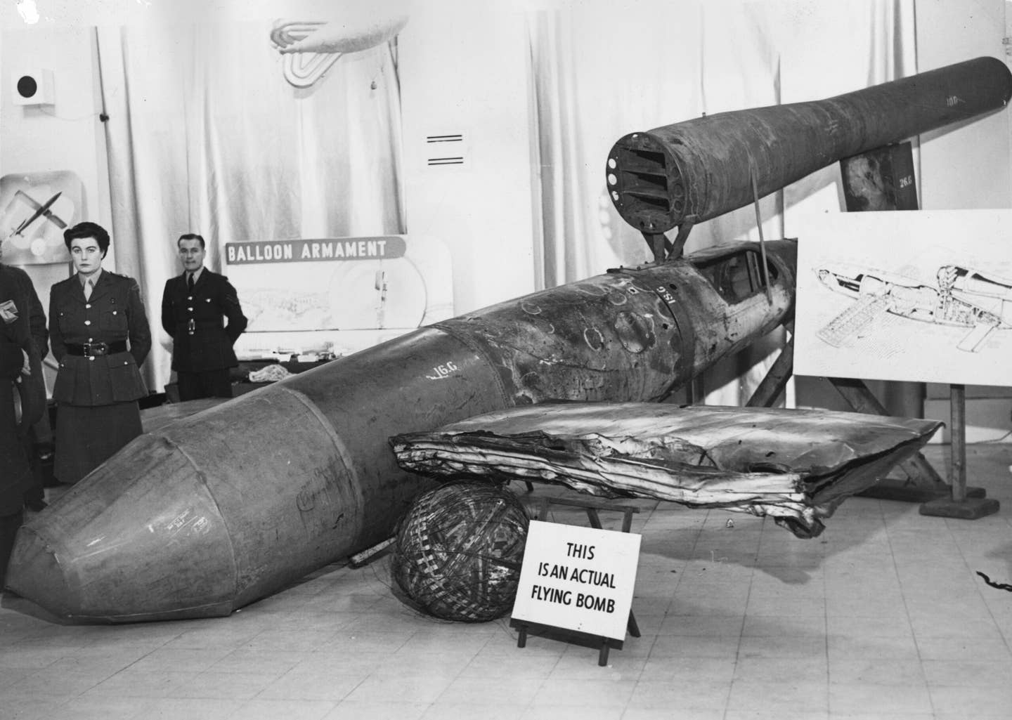 A V1 flying bomb, or Doodlebug, on show at Roote's, Piccadilly, London, November 1, 1944. A sign next to the bomb reads "This is an actual flying bomb." <em>Photo by A. R. Coster/Topical Press Agency via Getty Images.</em>