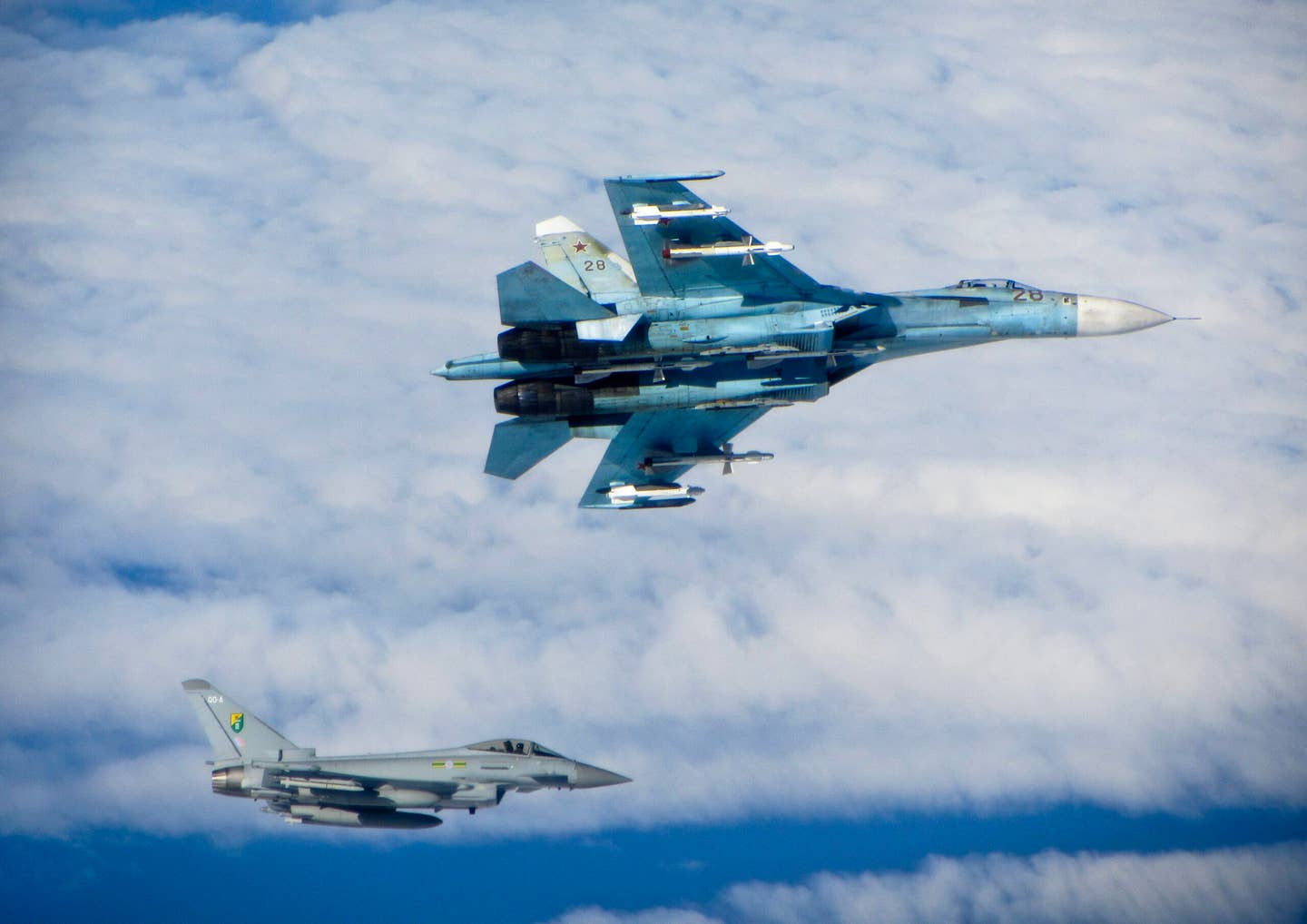 A Russian Su-27 Flanker banks away from an RAF Typhoon in international airspace over the Baltic Sea in June 2014. The Russian fighter is armed with a mix of radar- and infrared-guided R-27 and heat-seeking R-73 air-to-air missiles. <em>Crown Copyright</em>