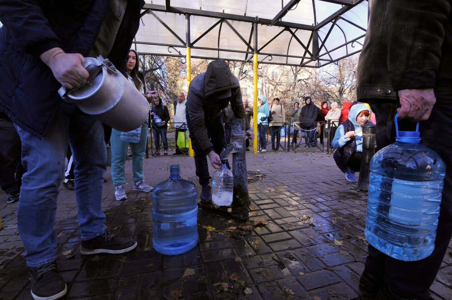 Local residents wait in line to collect water from a public water pump in a Kyiv park on Oct. 31, 2022. (Photo by SERGEI CHUZAVKOV/AFP via Getty Images)